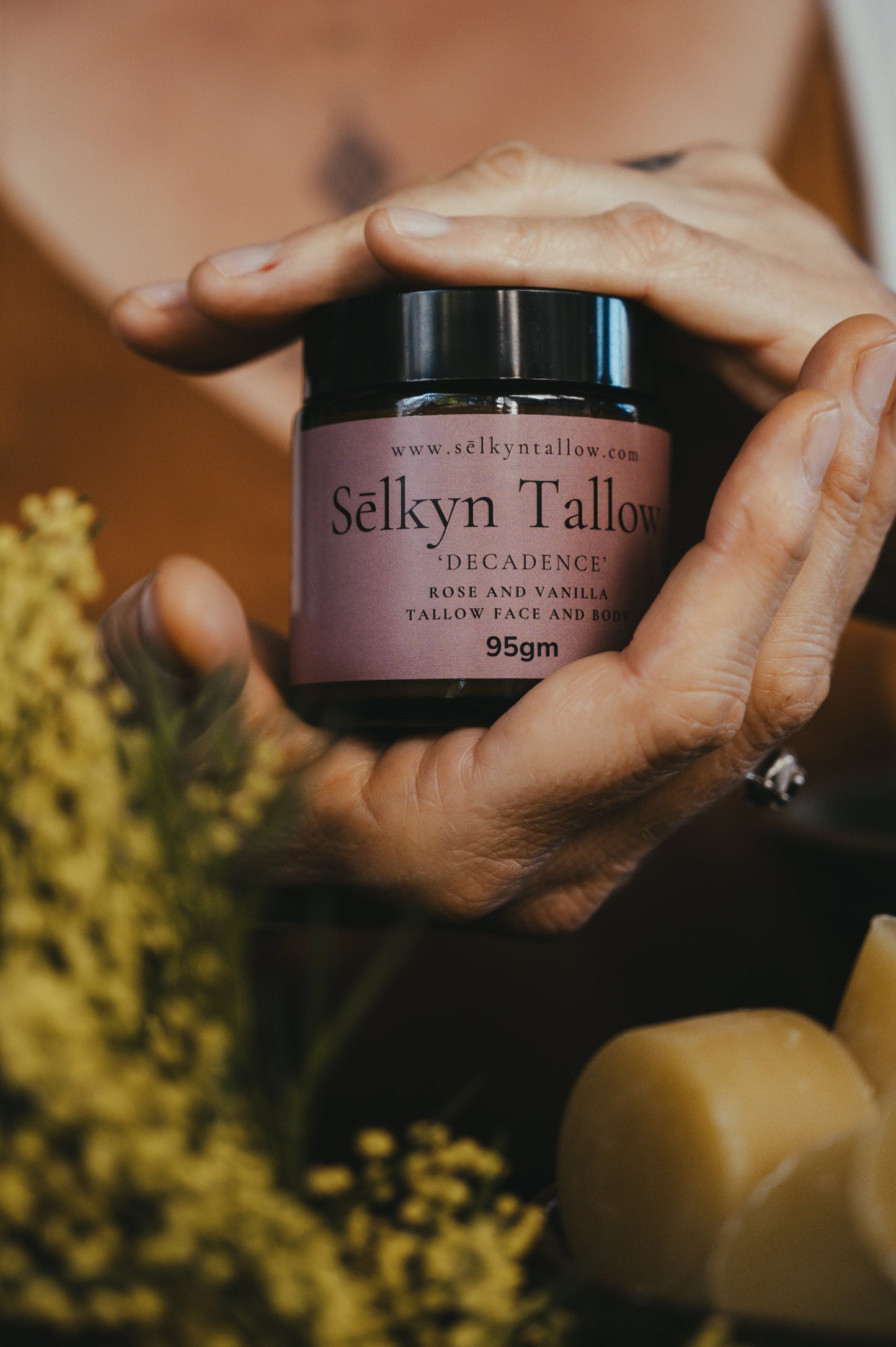 organic tallow skincare balm held in natural botanical setting